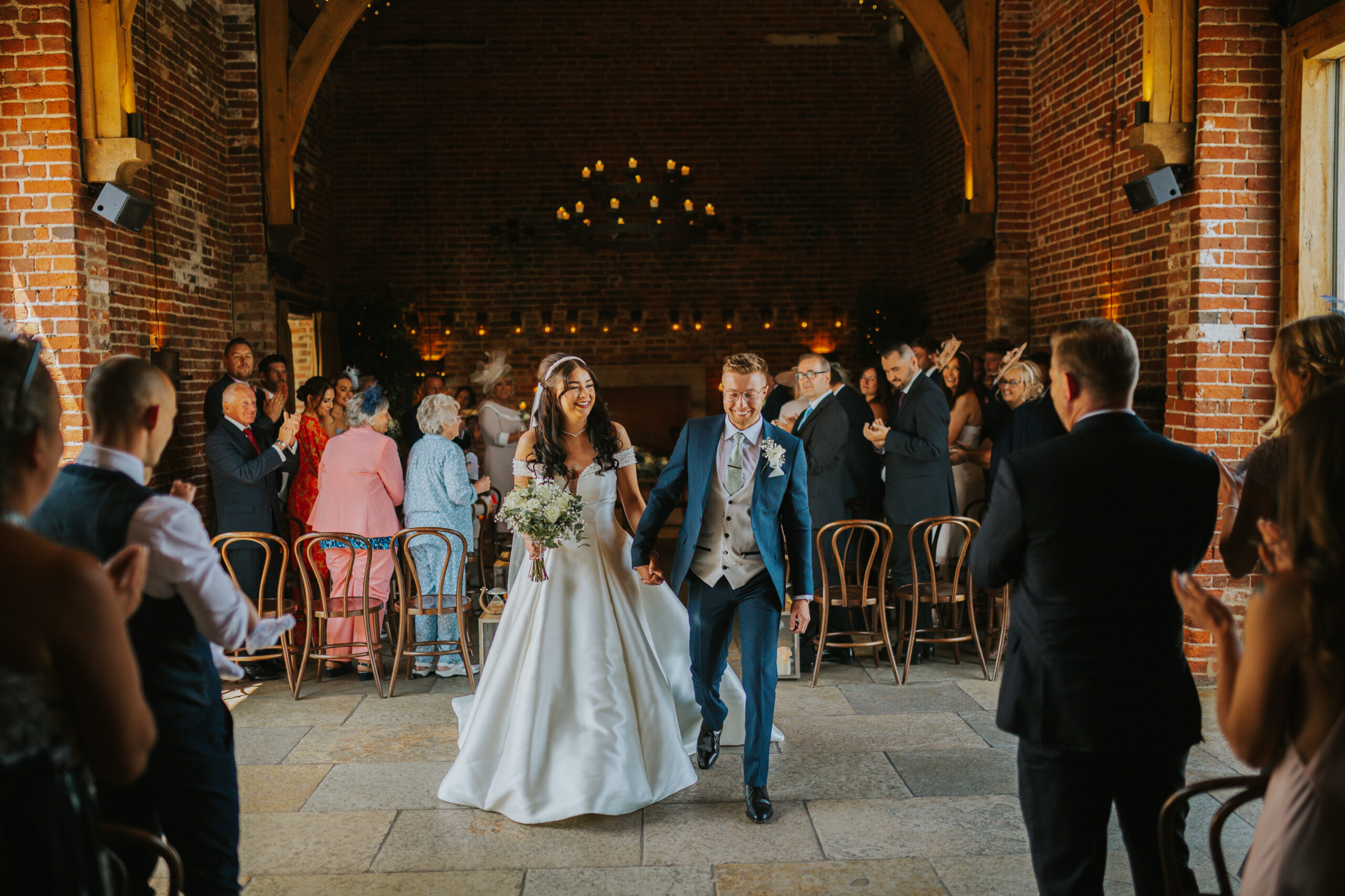 Recently married couple on their wedding day, walking back down the aisle after saying 'I Do'. At Hazel Gap Barn, part of the Cripps & Co family. Photograped by Slate Cottage Studio.