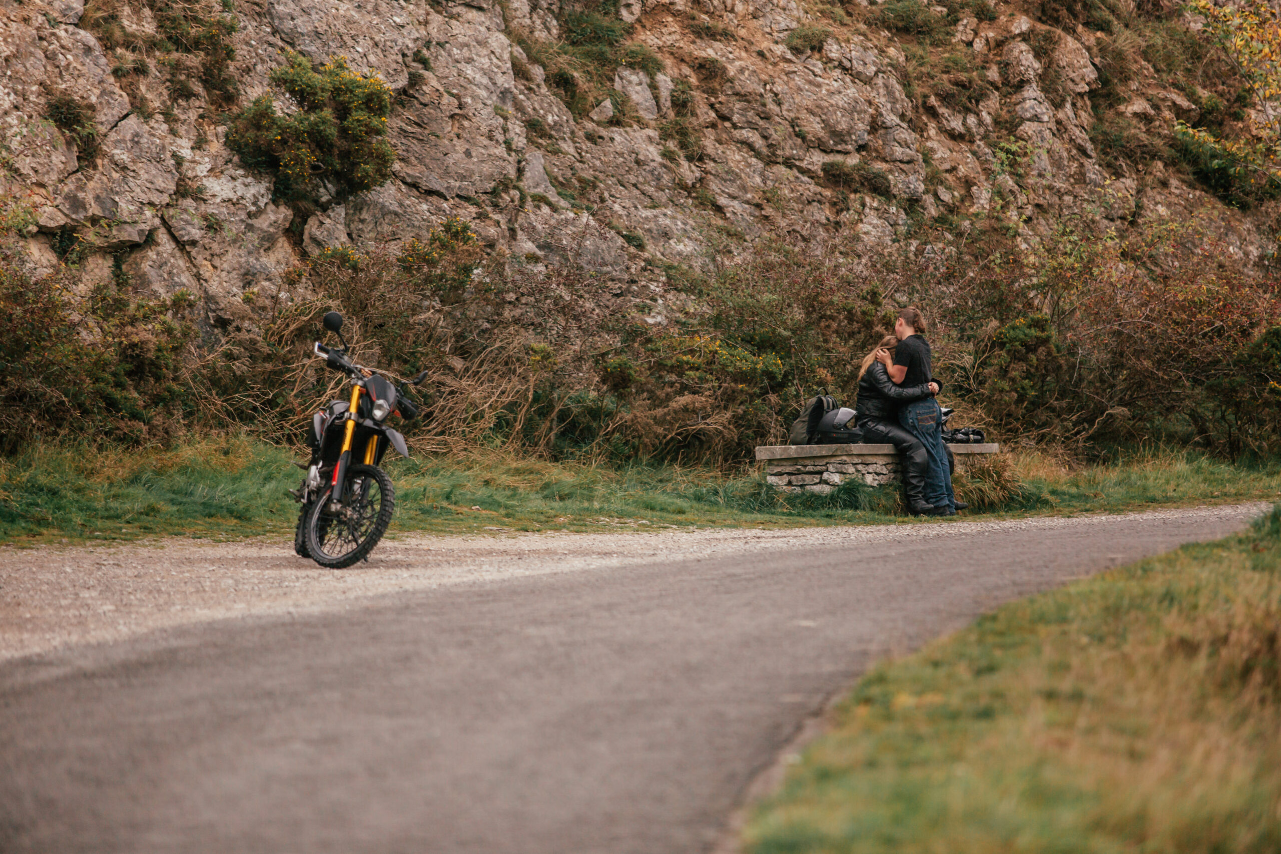 Motorbike and couple sharing a moment after a surprise proposal in the Peak District. Unique and adventurous engagement photography setting.