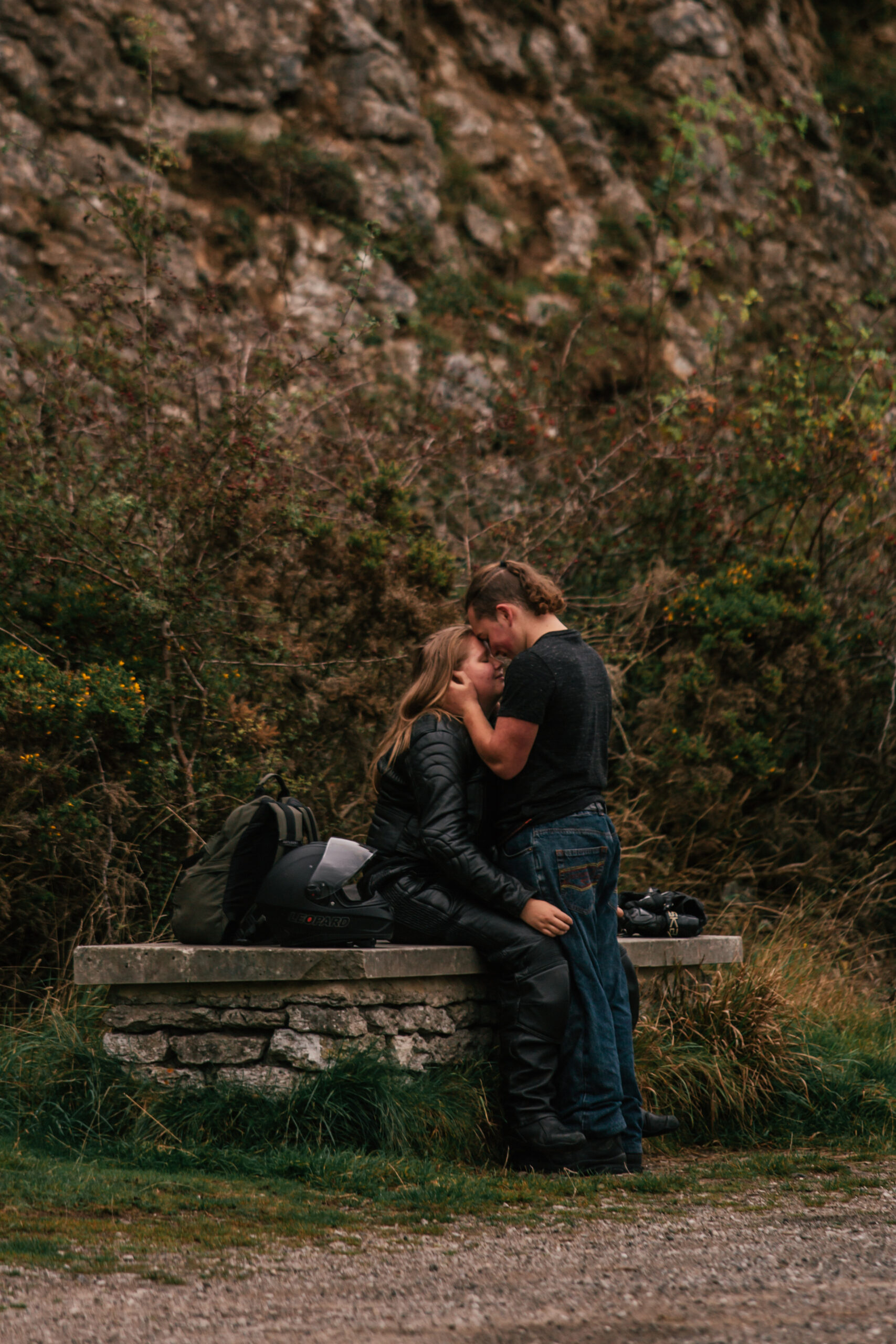 A surprise Peak District proposal captured as a couple sits together under a rocky landscape, highlighting the intimate, natural setting.