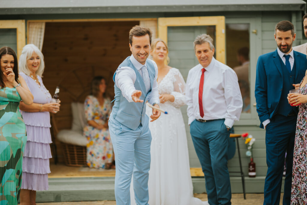 Guests mingling and enjoying games at a back garden wedding reception, featuring hay bales and rustic details for a relaxed, unique wedding celebration.