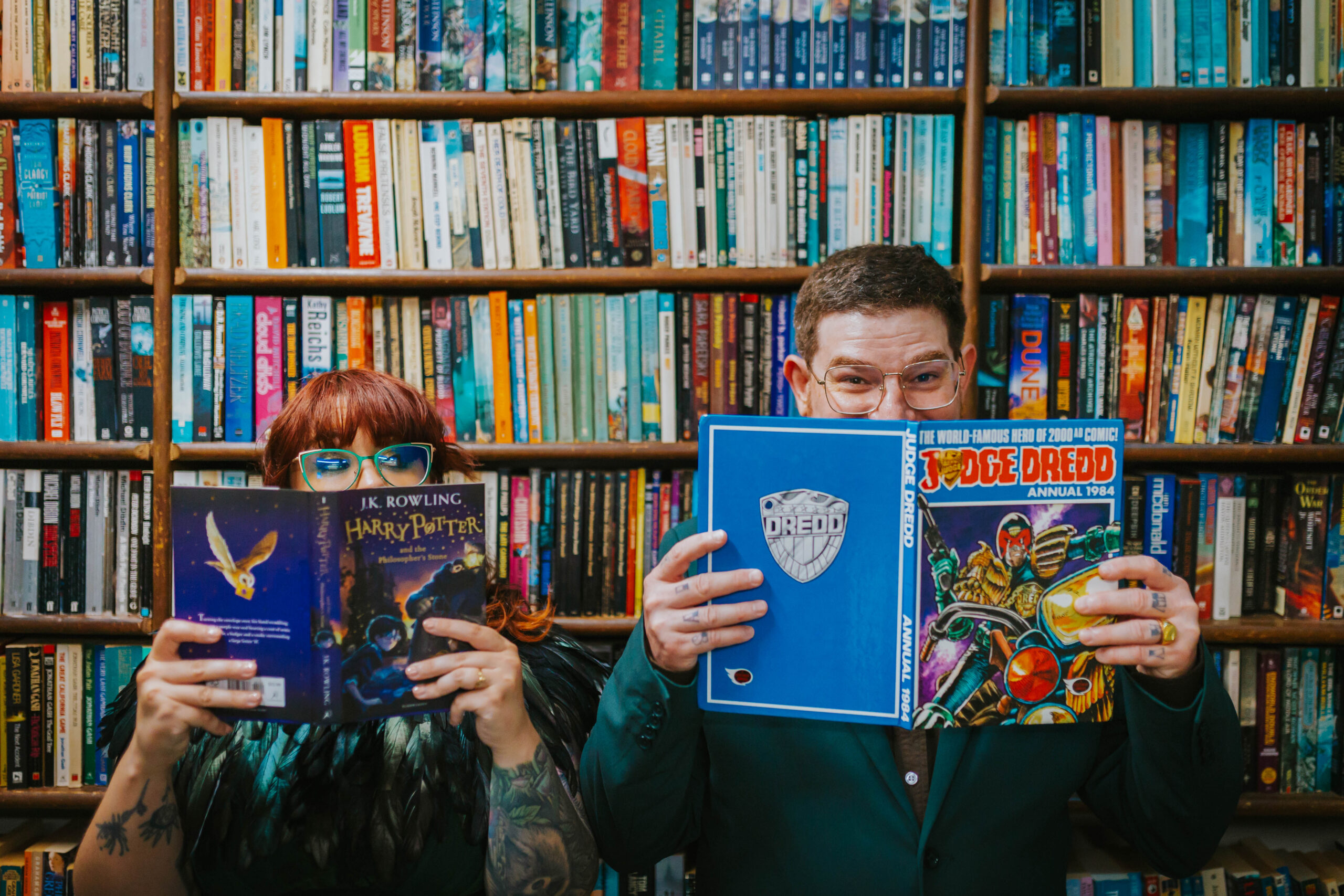 A couple playfully posing with books in a library during their wedding shoot, highlighting their quirky personalities. Perfect for alternative wedding photography in Manchester.