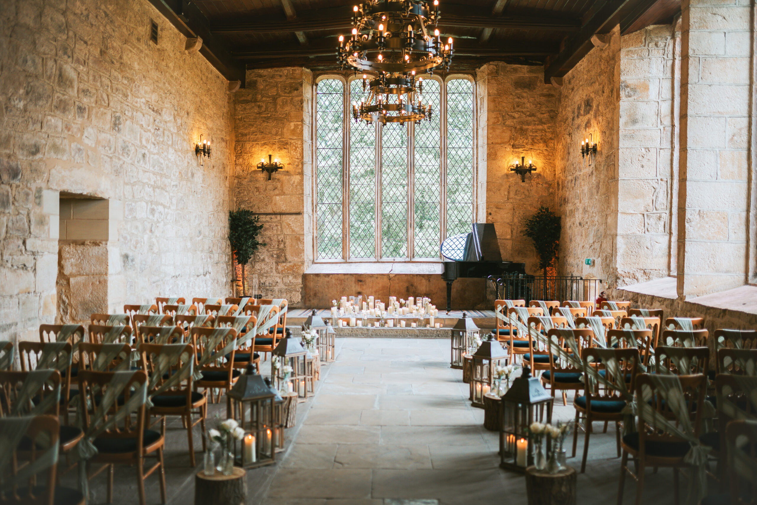 The breathtaking interiors of The Priests House, Skipton, showcasing elegant chandeliers, large windows, and a romantic candlelit ceremony setting. Photographed by Slate Cottage Studio.