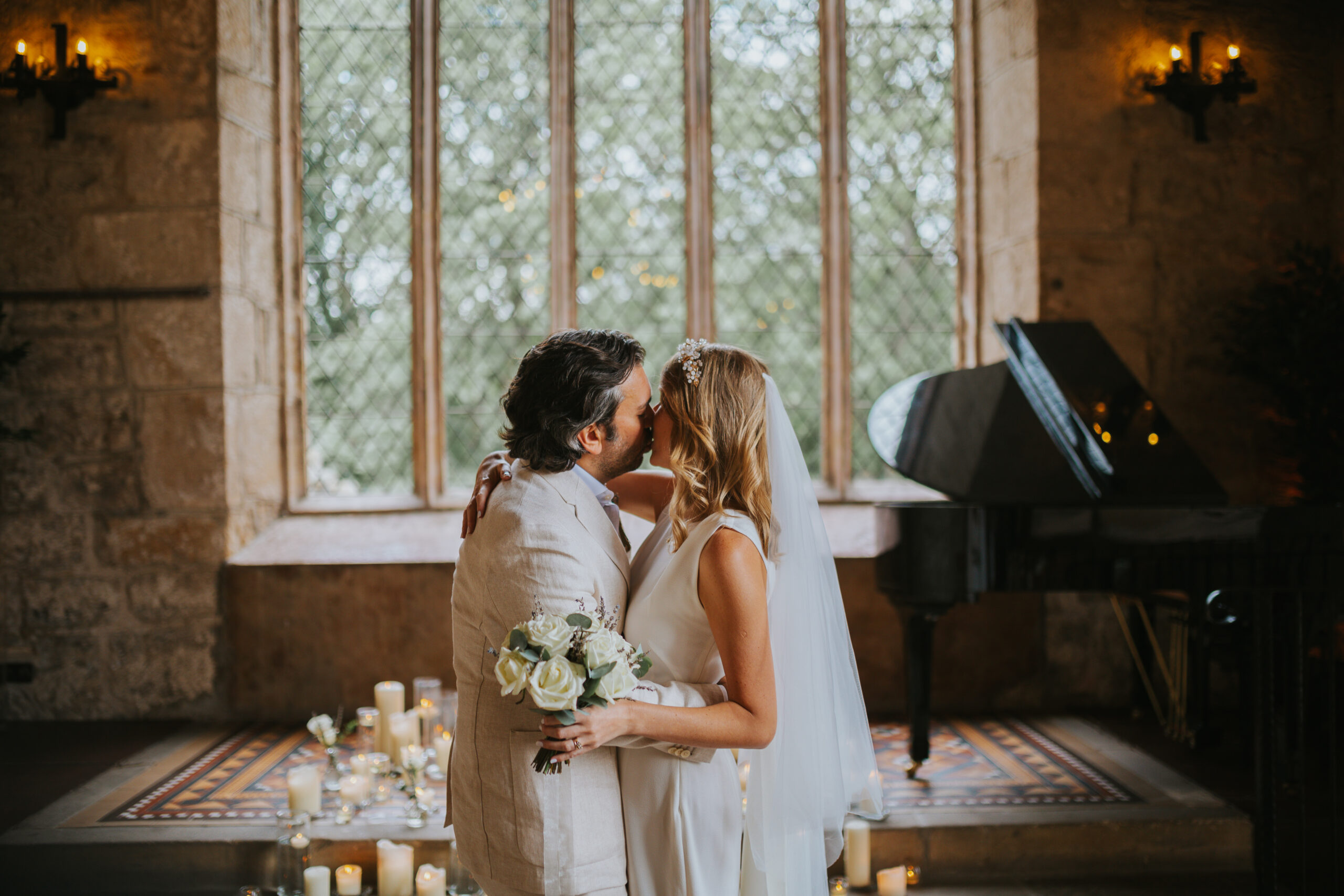 Bride and groom kissing during their intimate wedding ceremony at The Priests House in Skipton, surrounded by candles and historic stone interiors in the Yorkshire Dales. Perfect setting for natural and romantic wedding photography. Photographed by Slate Cottage Studio.