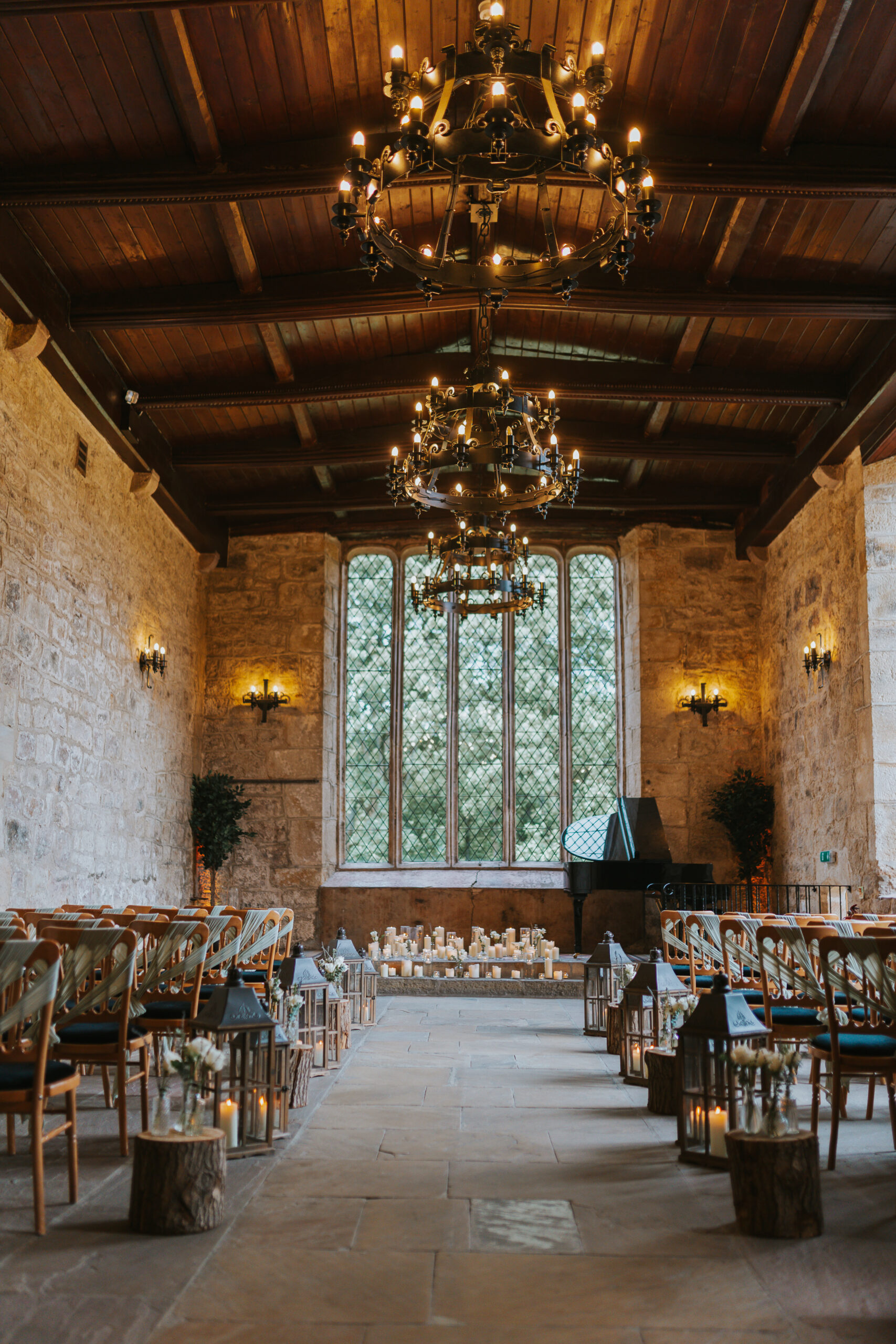 The breathtaking interiors of The Priests House, Skipton, showcasing elegant chandeliers, large windows, and a romantic candlelit ceremony setting. Photographed by Slate Cottage Studio.