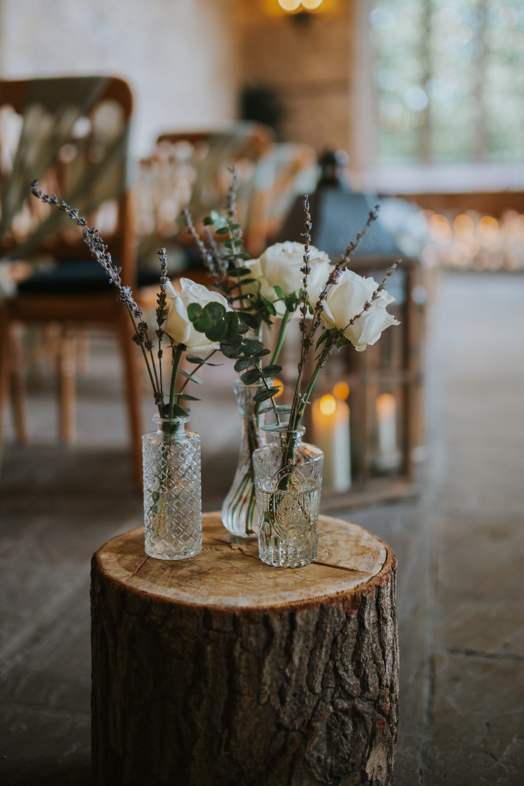 Delicate white roses and greenery in vintage glass vases at The Priests House, Skipton. A perfect touch of rustic elegance for a wedding in the Yorkshire Dales. Photographed by Slate Cottage Studio.