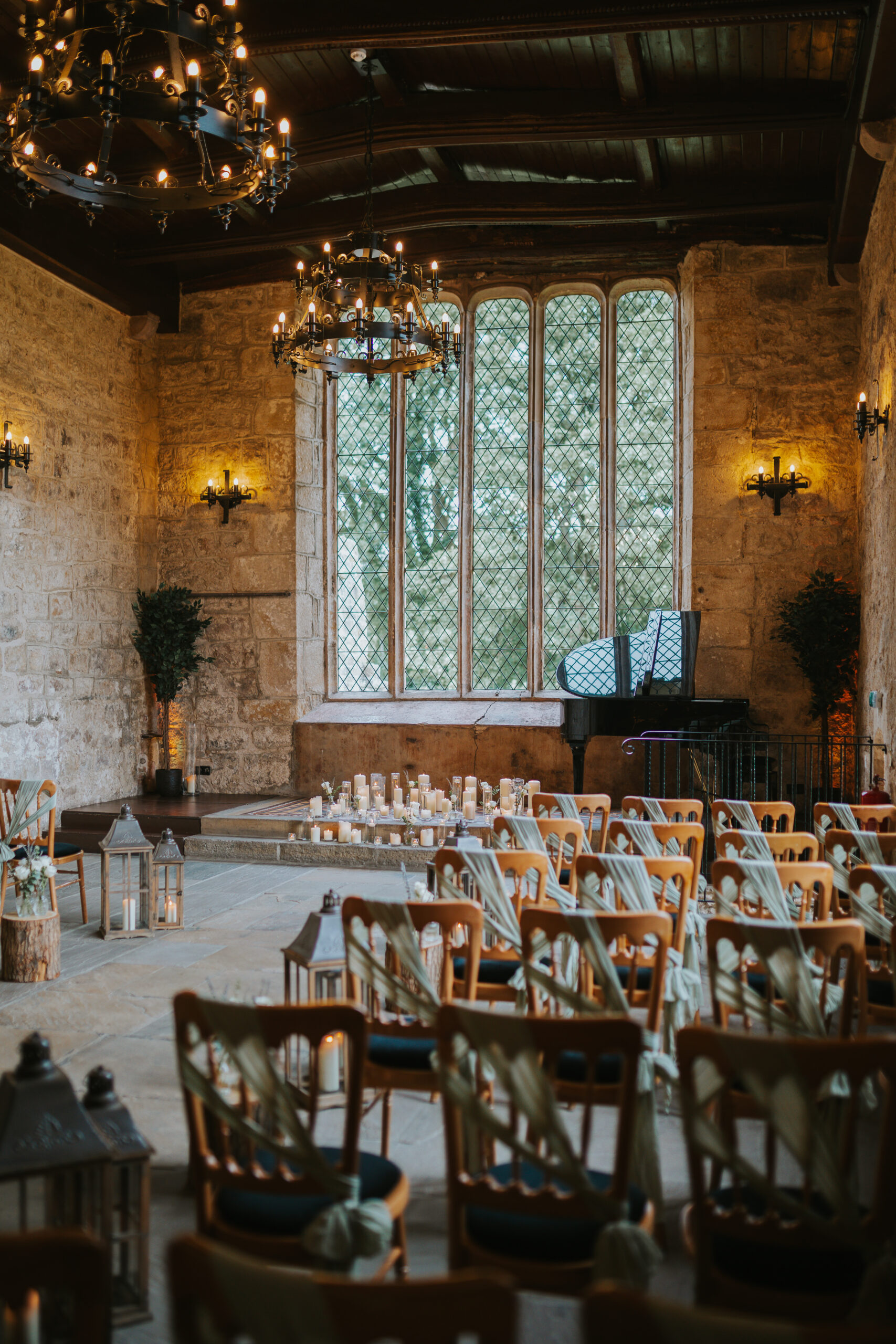 The Priests House in Skipton, set for a beautiful wedding ceremony with rustic wooden chairs, candlelight, and greenery in the romantic Yorkshire Dales. Photographed by Slate Cottage Studio.